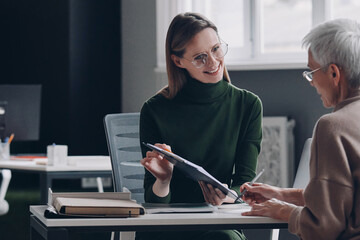 Wall Mural - Senior woman having a meeting with financial advisor while sitting in the office together