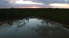 Aerial: Drone Forward Shot Of Reflection Of Clouds In Tranquil Pond By Green Trees Under Cloudy Sky At Sunset - Daytona Beach , Florida