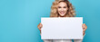 Happy woman looking at a camera holding a white sign on a blue background - copy space mockup