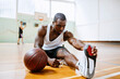 © Marko Geber - Young man stretching before playing basketball in an indoor basketball gym