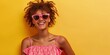 Young woman wearing funky retro sunglasses and pink dress on yellow background