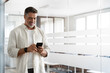 © Stock 4 You - Smiling mature Latin or Indian businessman holding smartphone in office. Middle aged manager using cell phone mobile app. Digital technology application and solutions for business success development.