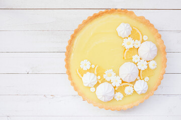 Poster - Spring lemon tart with white chocolate flowers and meringue. Above view over a white wood background.