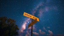"Dream Big" Text On A Yellow Signpost Against The Milky Way Background Captured At Nighttime