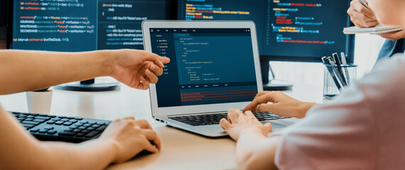 Two smart cooperative computer engineers working together as teamwork to solve program code while computer screen displayed program code. Laptop, web development, programer, java script . Burgeoning.