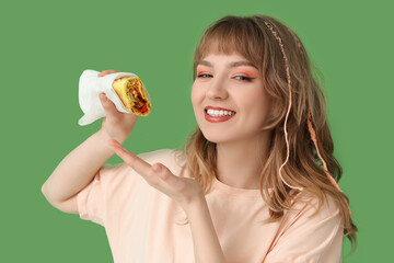 Sticker - Young woman with tasty sandwich wrap on green background, closeup