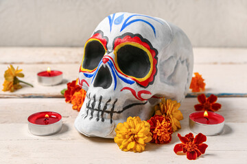 Poster - Painted human skull with burning candles and beautiful flowers for Mexico's Day of the Dead on white wooden table