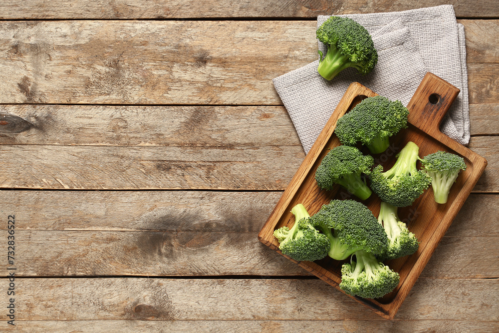 Board with fresh broccoli cabbages on wooden background