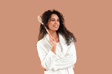 Poster - Young African-American woman in bathrobe with massage brush on brown background