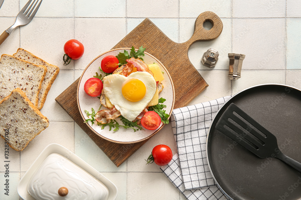 Composition with tasty fried egg, toasts, bacon, tomatoes and arugula in plate on light tile background