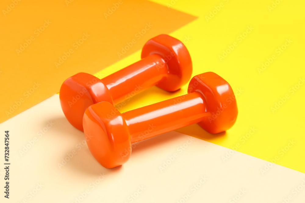 Orange dumbbells on color background
