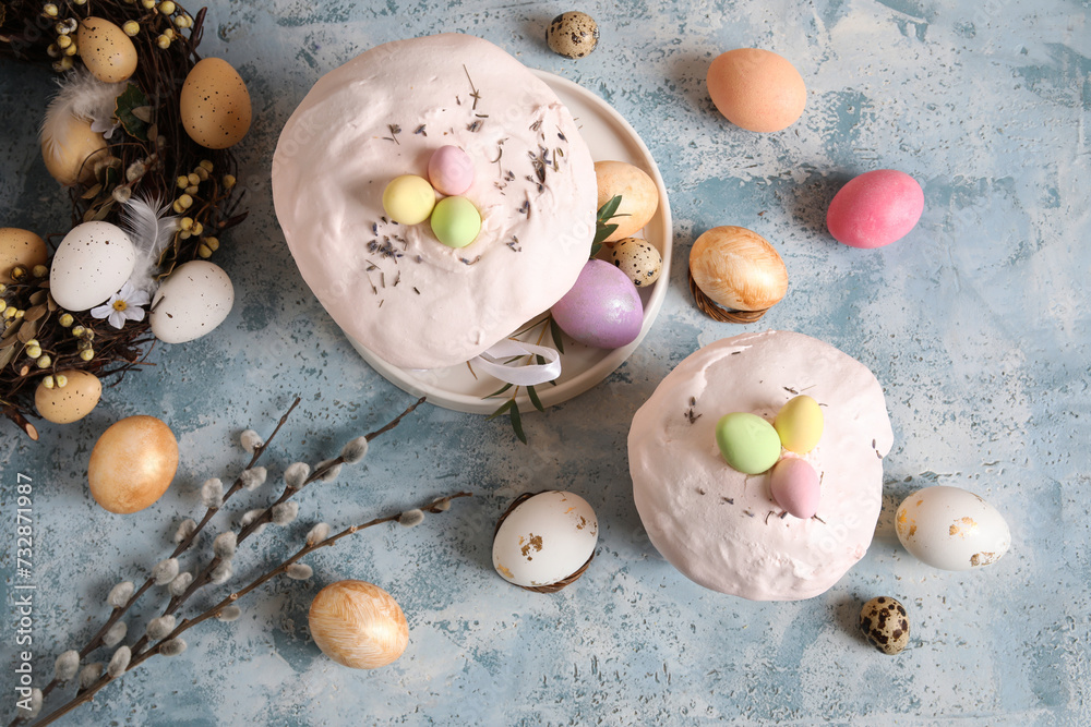 Composition with delicious decorated Easter cakes and painted eggs in plate on color background. Top view