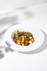 Wall Mural - Mediterranean salad with octopus, potatoes, tomatoes, and Kalamata olives in a spicy sauce, shadowed on a white background