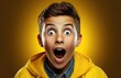 Young guy with a surprised face and open mouth on a yellow background