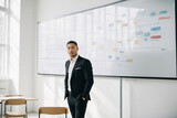 Fototapeta Sawanna - One man in black suit in the classroom in front of the white board witn tables and diagrams.