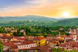 © Yaroslav - travel summer view from hill to a nice european town with amazing buildings, green hills and mountains with amazing cloudy evening sky on background