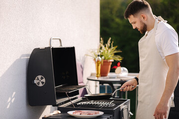 Wall Mural - Middle selection of man in apron using wooden spoon to mix vegetables on frying pan. Prepare food on grill