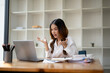 © Wasana - Young businesswoman with a surprised expression while looking at her laptop screen in a modern office setting..