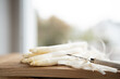 Freshly peeled white asparagus on wooden cutting board. Bright kitchen scene with spring vegetables for the seasonal gastronomy. Short depth of field.