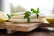 Lying bunch of fresh white asparagus. Seasonal spring vegetables with parsley and lemon on wooden cutting board. Kitchen scene for the seasonal gastronomy.