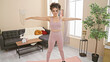 © Krakenimages.com - Young hispanic woman with curly hair practicing yoga in a cozy living room, portraying health and wellness at home.