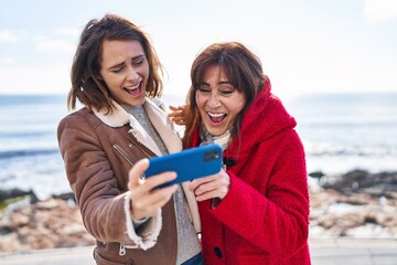 Wall Mural - Two women mother and daughter using smartphone at seaside