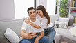 © Krakenimages.com - Couple selfie indoors with woman embracing man on couch, showcasing love and togetherness in a modern living room setting.