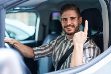 Poster - Hispanic man with beard driving car smiling with an idea or question pointing finger with happy face, number one