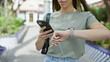 © Krakenimages.com - Outdoor shot, woman's hands caught texting time countdown on smartphone watch at park amidst city bustle