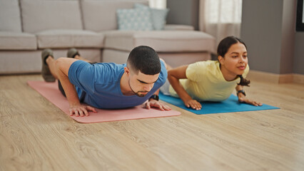 Wall Mural - Beautiful couple showcasing power and love, training together with indoor push up workout at home