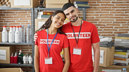 Sticker - Smiling man and woman volunteers enjoy hugging each other, standing in charity center, unity in volunteer work