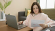 © Krakenimages.com - A focused young woman analyzes financial documents while working from home, creating a relatable indoor lifestyle scene.