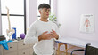 © Krakenimages.com - At his balance point, a portrait of a young, handsome hispanic man finding calm by meditating and taking a deep breath, relaxing in the indoor room of a rehab clinic, conquering respiratory problems