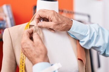 Poster - Middle age grey-haired man tailor sewing jacket on manikin at atelier