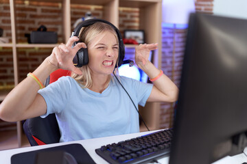 Poster - Young caucasian woman playing video games wearing headphones smiling funny doing claw gesture as cat, aggressive and sexy expression