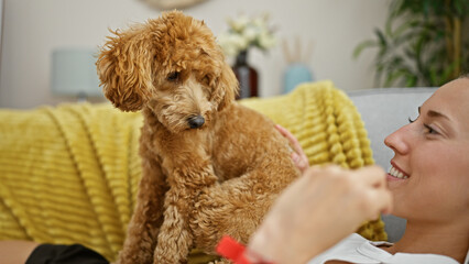 Wall Mural - Young caucasian woman with dog lying on the sofa playing at home