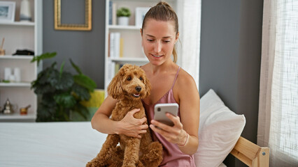 Wall Mural - Young caucasian woman with dog using smartphone sitting on the bed at bedroom