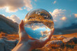 Shot of person holding a crystal ball with cloud reflections in blue sky.