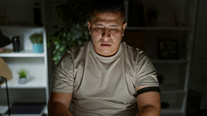 Sticker - Young latin man at work, a portrait of serious business worker, confidently sitting in his dim office at night