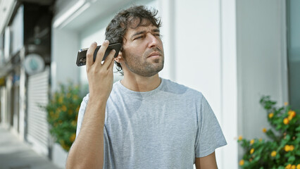 Canvas Print - Young man listening to voice message at the street