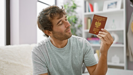 Canvas Print - Handsome blond young man, a confident patriot, joyfully smiling with his polish passport, casually lounging on his living room sofa, ready for european holiday adventures!