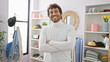 © Krakenimages.com - Handsome hispanic man with beard smiling in a modern wardrobe room, arms crossed, wearing a white sweater.