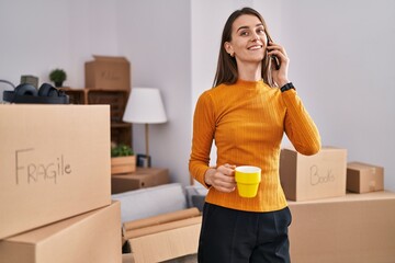 Sticker - Young caucasian woman talking on smartphone drinking coffee at new home