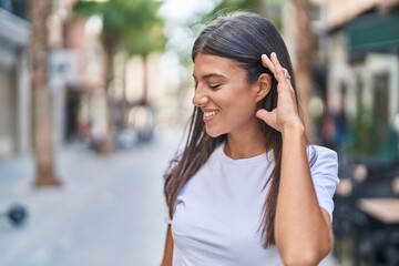 Canvas Print - Young beautiful hispanic woman smiling confident combing hair with hands at coffee shop terrace