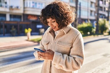 Wall Mural - Young beautiful hispanic woman smiling confident using smartphone at street