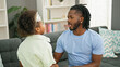 © Krakenimages.com - African american father and daughter smiling confident sitting on sofa together speaking at home