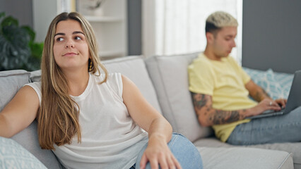 Wall Mural - Beautiful couple sitting on sofa using laptop having problems at home