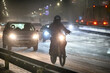 Zimą człowiek na motocyklu jedzie ślizgom drogą. 
