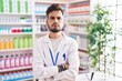 © Krakenimages.com - Young hispanic man with tattoos working at pharmacy drugstore skeptic and nervous, disapproving expression on face with crossed arms. negative person.
