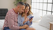 © Krakenimages.com - Man and woman couple sitting on bed using smartphone at bedroom